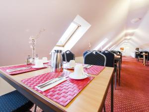 埃尔丁Andante Hotel Erding的一间带桌椅的用餐室和窗户。
