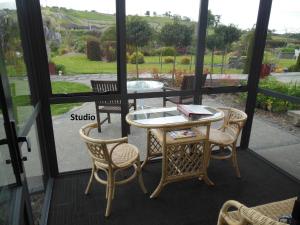 奥雷瓦Silverdale Garden Studio的庭院配有桌子和两把椅子,设有窗户。
