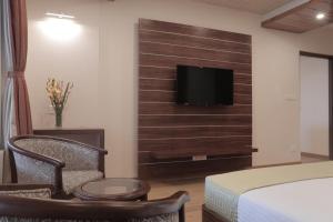 大吉岭Jai Hotels的一间卧室配有一张床,墙上配有电视