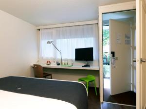 昂代昂达伊钟楼酒店的一间卧室配有一张床和一张带电脑的书桌