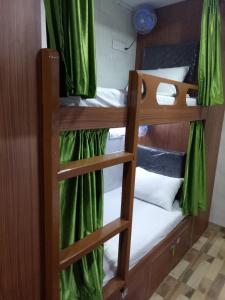 孟买Royal Dormitory的配有两张双层床的绿色窗帘客房