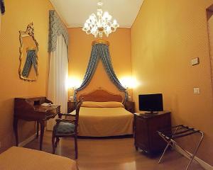 威尼斯坎达运河酒店的一间卧室配有一张带吊灯的床和一张书桌。