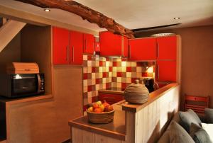 EngisLes houx de Mathieu的厨房配有红色橱柜和一碗水果放在桌子上
