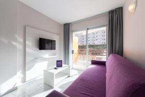 英格兰海滩埃奥拉斯加西拉斯公寓式酒店的一间卧室设有紫色的床和大窗户