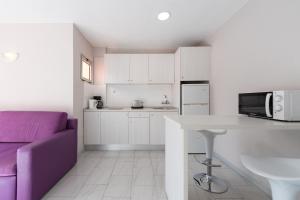 英格兰海滩埃奥拉斯加西拉斯公寓式酒店的厨房配有白色橱柜和紫色沙发