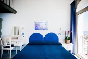 文托泰内尤利亚别墅酒店的卧室内的一张蓝色的床,配有一张书桌和一个窗户