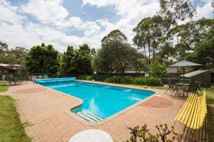 卡尔斯Phillip Island Park Lane Holiday Park的一个带砖砌庭院和黄色椅子的游泳池