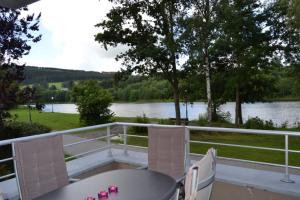 维尔雅尔姆la terrasse du lac的阳台配有桌椅,享有河景
