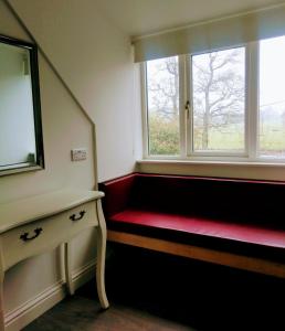 亚达尔The Hollies的一间设有红色长凳和窗户的房间