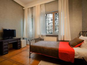 第比利斯Hotel Toma's House的一间卧室设有一张床、一台电视和窗户。