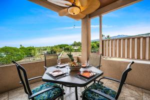 科纳科纳海岸卡哈路海滩别墅的阳台配有桌椅和吊扇