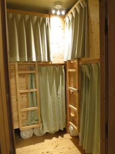 东京无国界旅馆的配有绿色窗帘的客房内的一张双层床