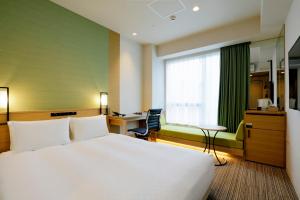 东京东京新桥光芒酒店的酒店客房设有一张大床和一张书桌。