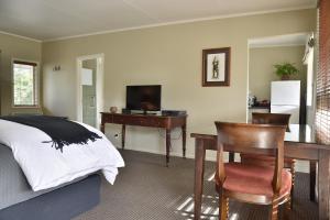 陶马鲁努伊布拉德利花园住宿加早餐旅馆的一间卧室配有书桌、一张床、一张桌子和椅子