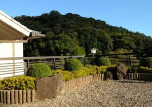 伊豆之国市Izu Nagaoka Kinjokan的一座房子前面的花园里有岩石和灌木