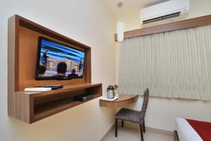 班加罗尔La Sara Comforts的配有电视、桌子和椅子的酒店客房