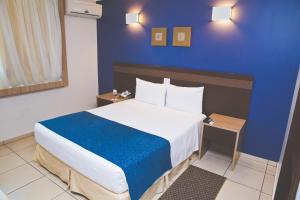阿拉拉夸拉阿拉拉夸拉康福特酒店的一间卧室设有一张蓝色墙壁的大床