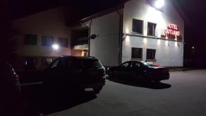 Wysokie MazowieckieHotel Gutland的两辆汽车晚上停在大楼前