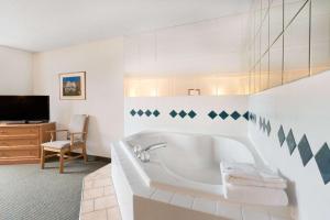 温泉城贝蒙特温泉套房酒店的带浴缸和电视的白色浴室