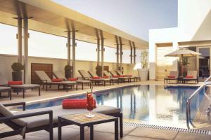 利雅德瓦哈中心罗塔纳酒店的酒店游泳池设有躺椅、桌子和桌子
