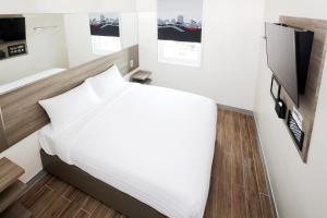 马尼拉Red Planet Cubao Aurora Boulevard的卧室配有白色的床和电视。