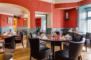 韦尔斯The Ancient Gatehouse & Rugantino Restaurant的一间带桌椅和红色墙壁的餐厅