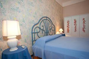 阿拉代奥B&B Li Culuri的一间卧室配有一张蓝色的床,桌子上配有一盏灯