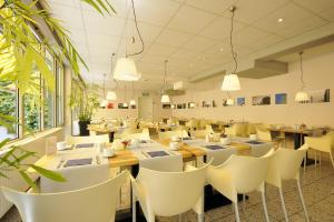 汉诺威Werkhof Hotel的配有木桌和白色椅子的餐厅