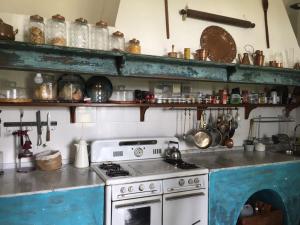 查斯科穆斯Estancia La Margarita的厨房配有炉灶和带锅碗瓢盆的架子。
