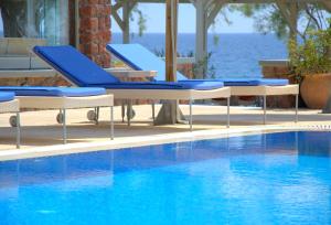 卡马利Thousand Stars Suites&Rooms的水边的游泳池,带蓝色椅子