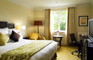 诺里奇Sprowston Manor Hotel, Golf & Country Club的配有一张床、一张书桌和一扇窗户的酒店客房