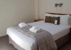 惠灵顿威利斯村酒店的卧室配有带毛巾的大型白色床