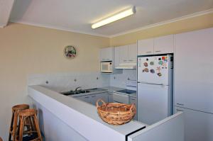 阳光海岸Bright & comfortable in quiet location的厨房配有白色橱柜和白色冰箱。