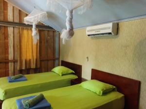 沙璜Iboih inn的配有绿床单和加热器的客房内的两张床