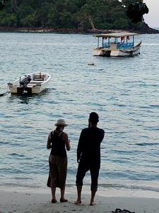 沙璜Iboih inn的两个人站在海滩上,在水中乘船