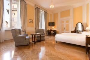罗马奎里纳莱酒店的一间卧室配有一张床、两把椅子和一张桌子