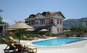 达利安İztuzu apart&villas的一座带游泳池、椅子和遮阳伞的大房子