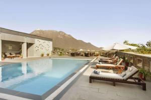 乌代浦华美达乌代布尔度假酒店的一个带躺椅的游泳池和一间酒店