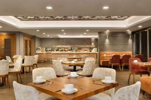 伯萨Ramada By Wyndham Bursa Cekirge Thermal & Spa的一间带桌椅的餐厅和一间厨房