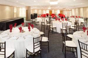 惠灵行政广场费尔布里奇酒店的宴会厅配有白色的桌子和椅子及红色玫瑰