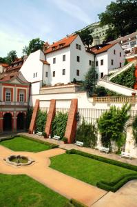 布拉格黄金井酒店的一座白色的大建筑,前面有一个花园
