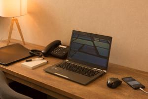坂井市九重福井酒店的一台笔记本电脑坐在一张桌子上,并带电话