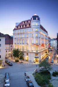 慕尼黑Mandarin Oriental, Munich - Germany's Best City Hotel 2024的一座白色的大建筑,汽车停在停车场