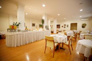 沙佩科Eston Hotel - LOCALIZAÇÃO CENTRAL PRIVILEGIADA -PET FRIENDLY的一间设有白色桌椅的餐厅和一间酒吧