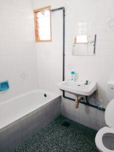 波德申Pandai dickson Banglow white & yellow house的一间带水槽、浴缸和卫生间的浴室