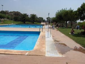 CastellnovoApartamentos Rurales San Juan的公园里的一个游泳池,人们坐在草地上