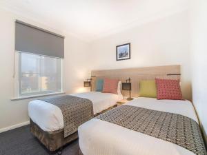墨尔本Melbourne South Yarra Central Apartment Hotel Official的一间卧室设有两张床和窗户。