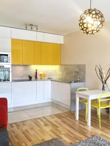 华沙ClickTheFlat Artistic Estate Apartment的厨房配有白色橱柜、桌子和黄色椅子