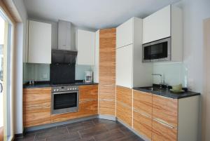 施库尔Feriendorf Uorsin的厨房配有白色和木质橱柜以及微波炉。