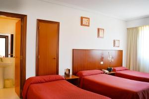 Pereiro de AguiarHotel Os Caracoles的酒店客房,配有两张床和红色床单